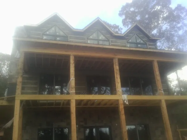 Dormers and porch framing on a large log home under construction — Roof Coating work by our crew in Saint Ansgar