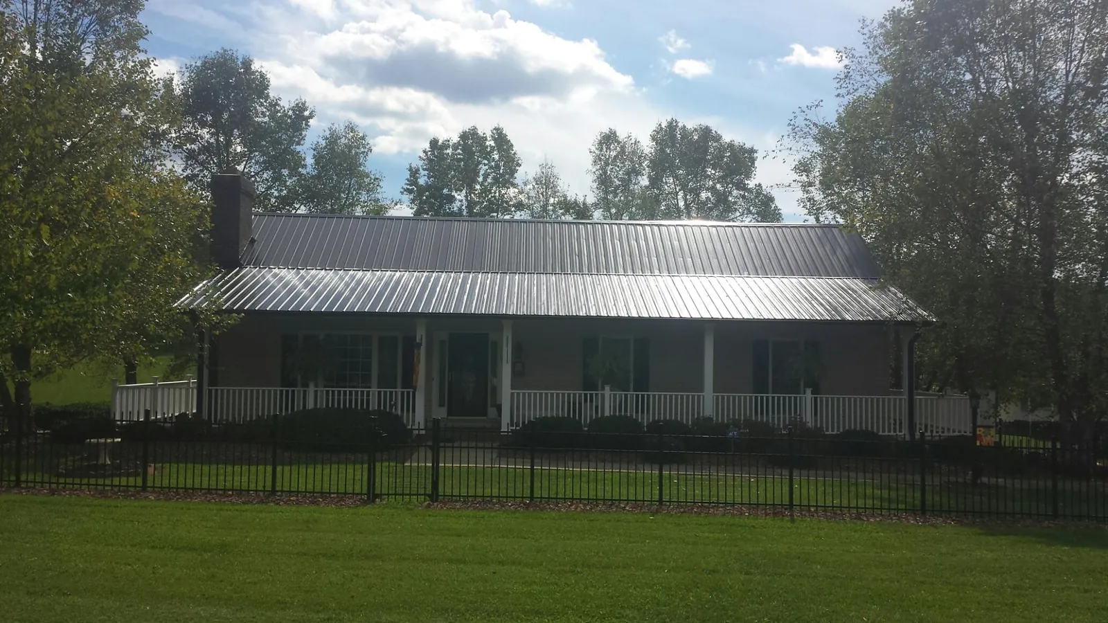 Gray metal roof on a brick ranch with a full width front porch — Gutter Guard Installation work by our crew in Saint Ansgar